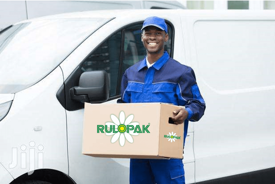 Livreur Cleans SARL portant un carton Rulopak devant la camionnette